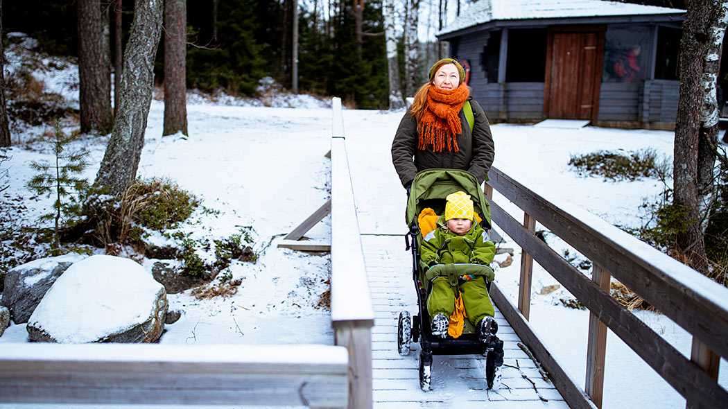 En snöig barriärfri brygga där en mamma går med barnvagn.
