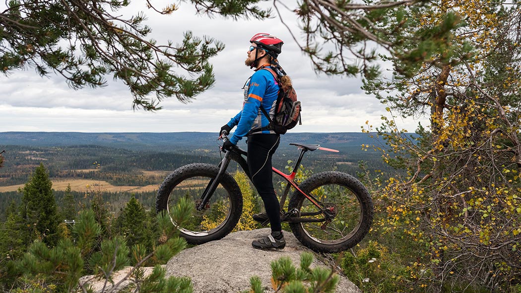 En mountainbikecyklist beundrar höstlandskapet från toppen av kullen.