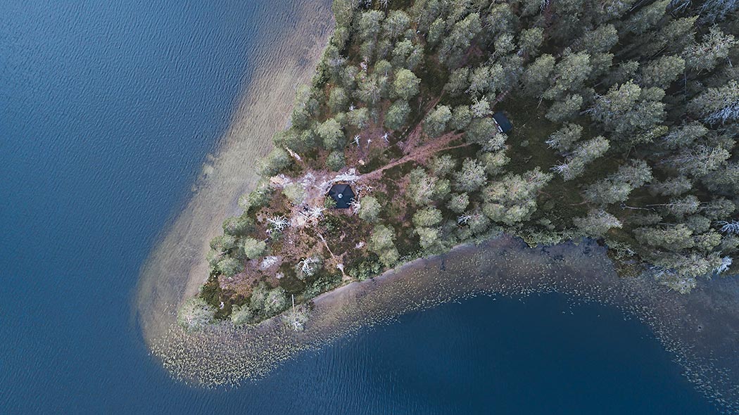Ett flygfotografi över en liten udde där det står en kåta.