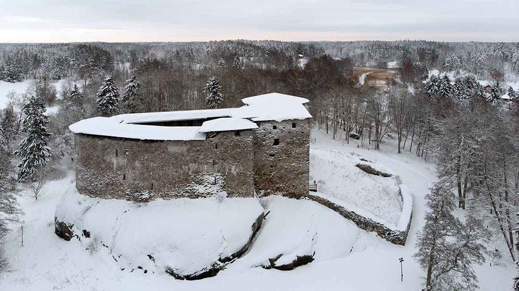 Flygfotografi taget vintertid. En stor gammal borg, delvis med tak, delvis utan.