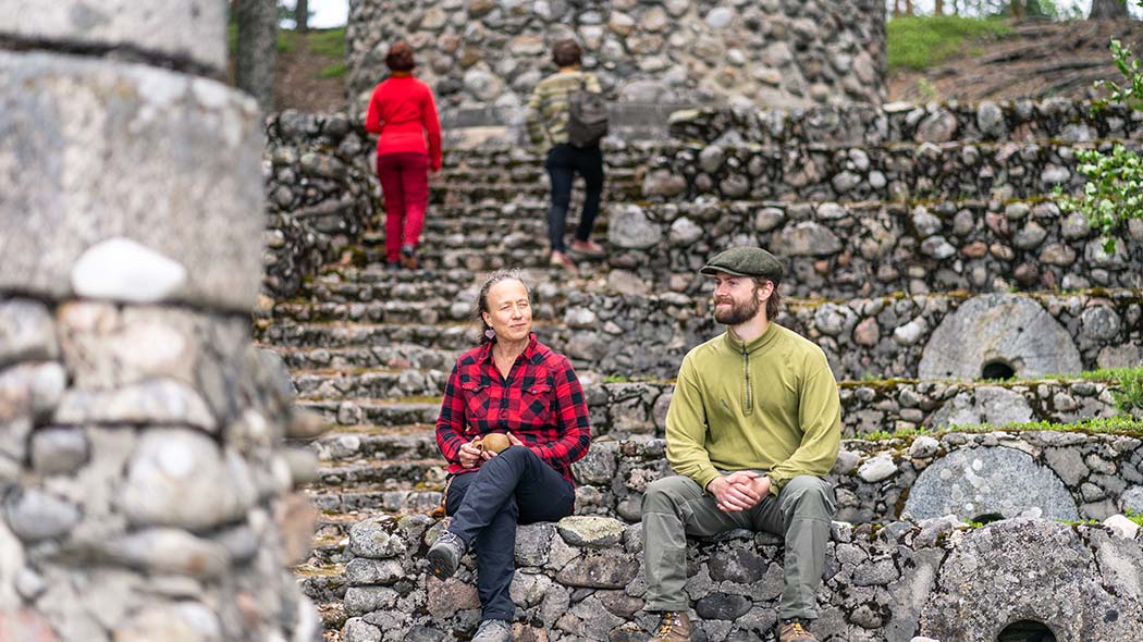 Två personer sitter på den låga stenmuren och två personer går uppför den invid liggande trappan.