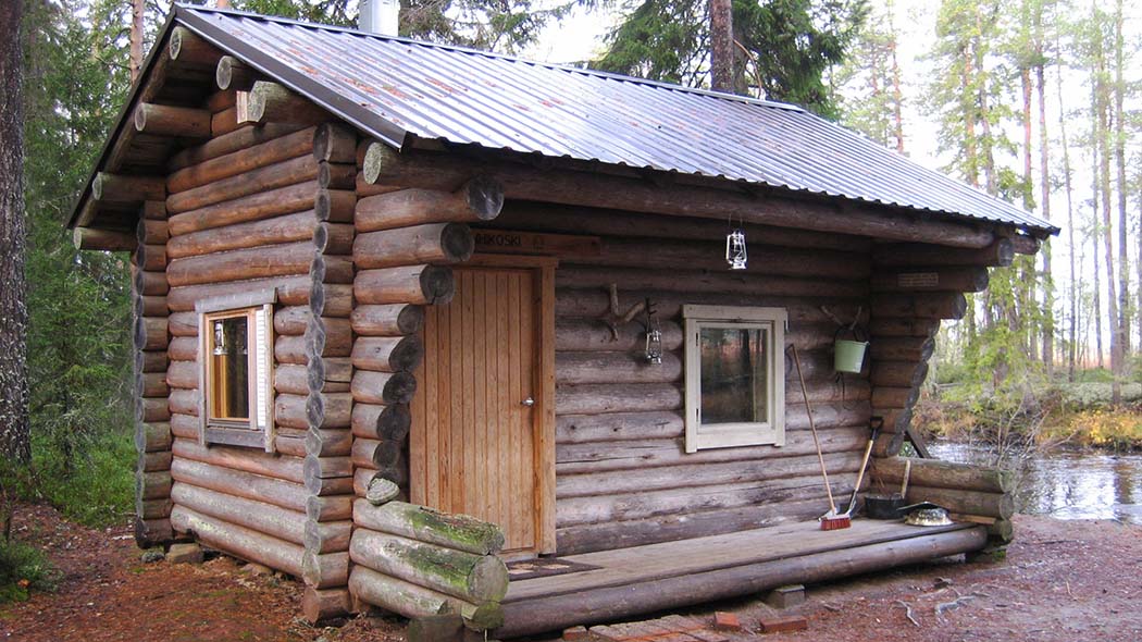 En stuga byggd av stockar i skogen.